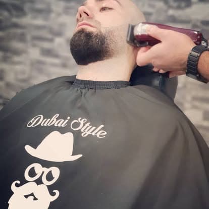 Een barber van Dubai Style werkt de baardcontour bij met een tondeuse.